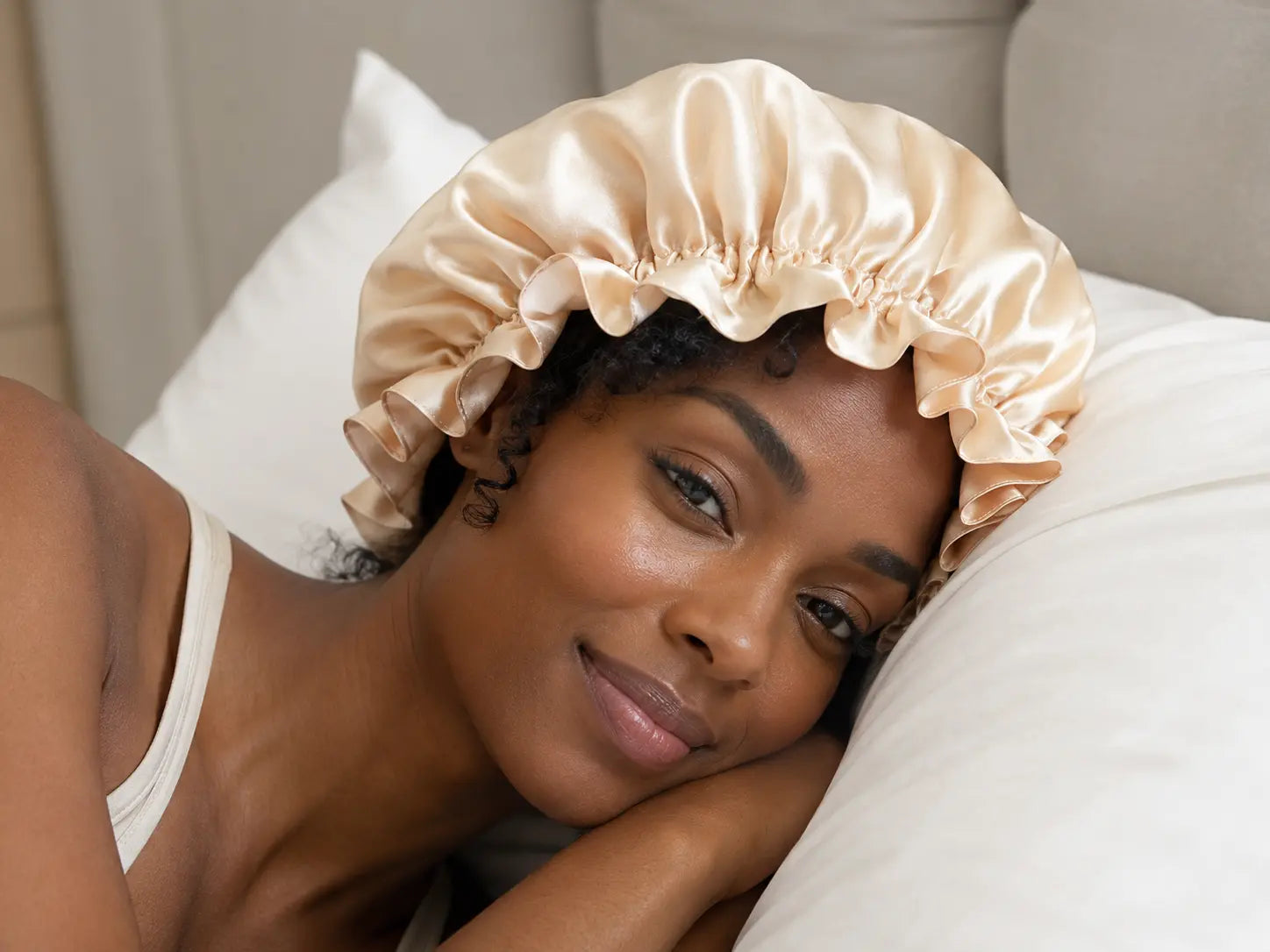 A curly-haired Black woman wearing a silk bonnet