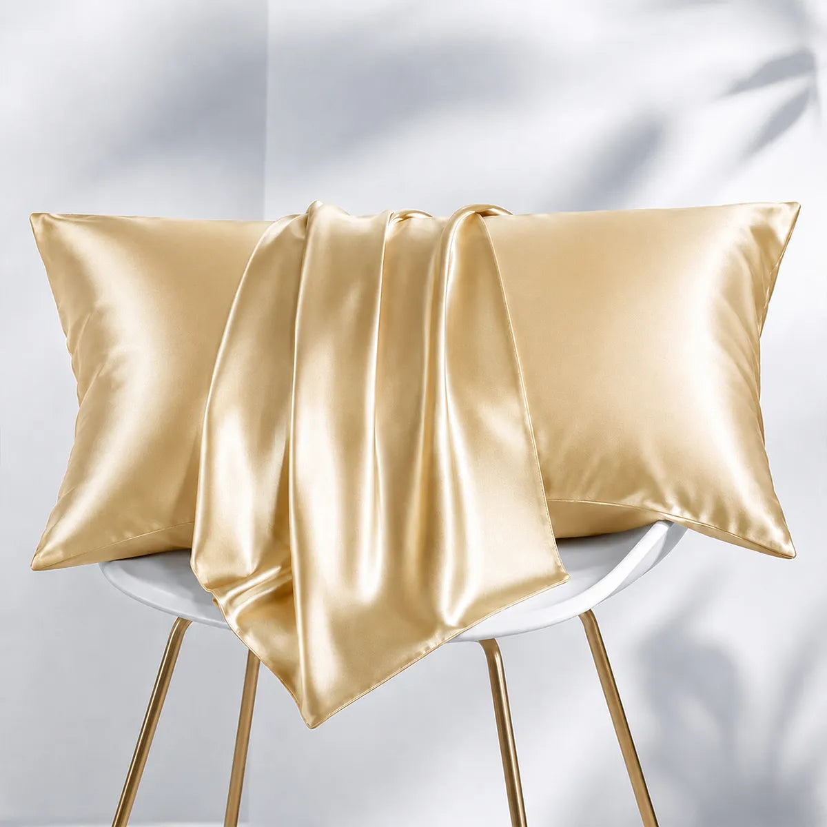 Champagne silk pillowcases with draped fabric on a chair